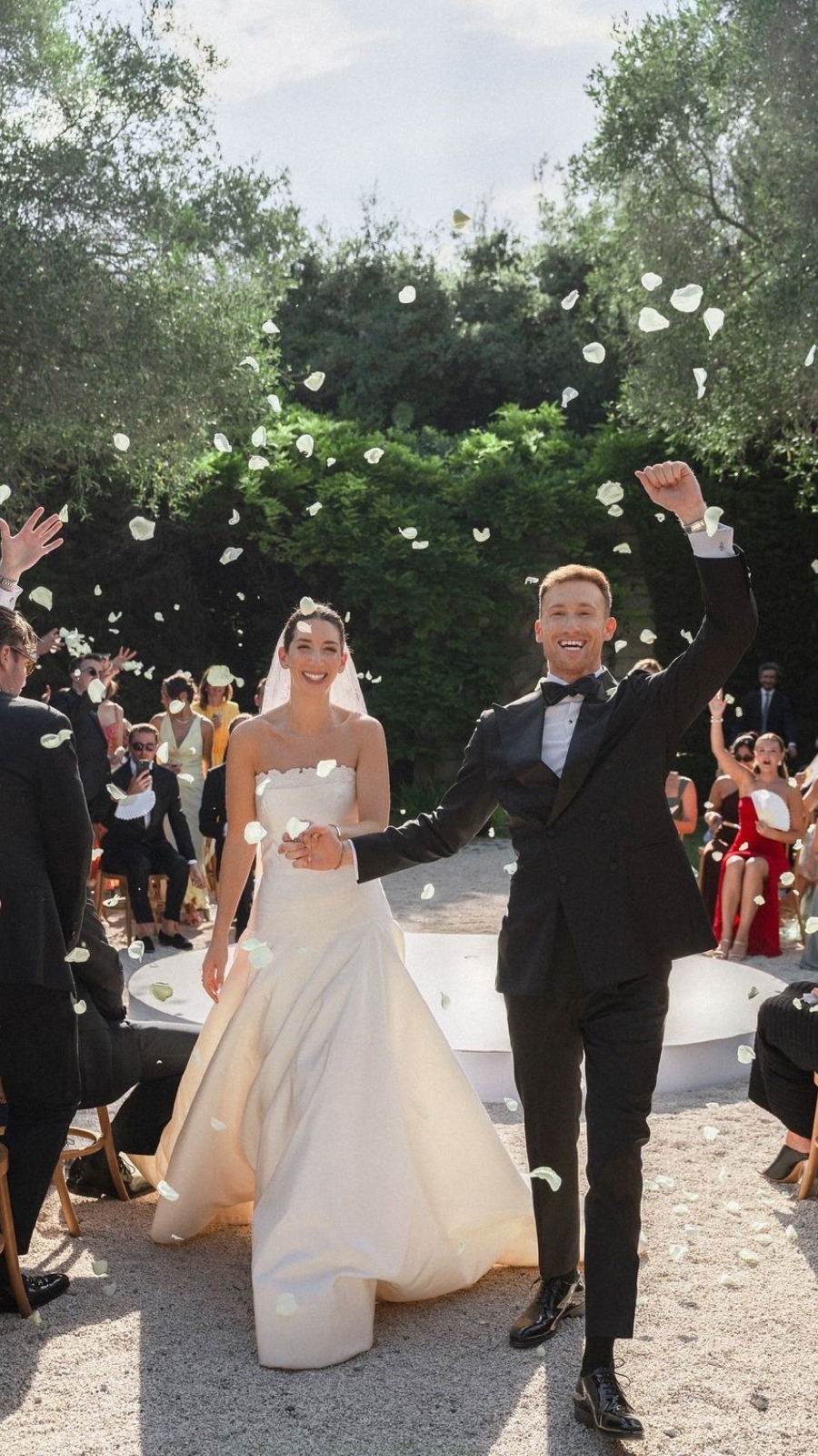 A couple walking back down the aisle through falling confetti.