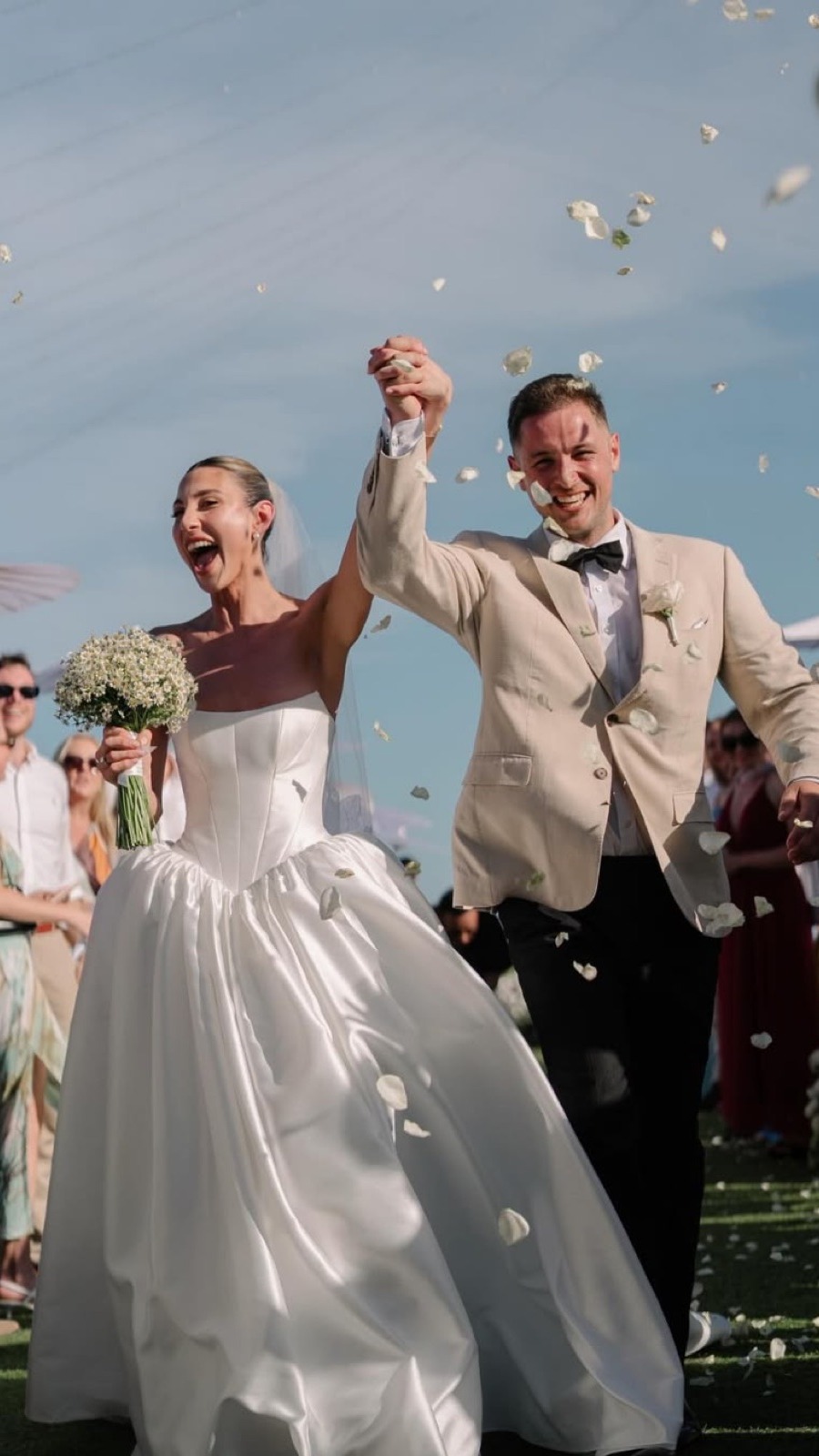A newly married couple cheering with their arms in the air.